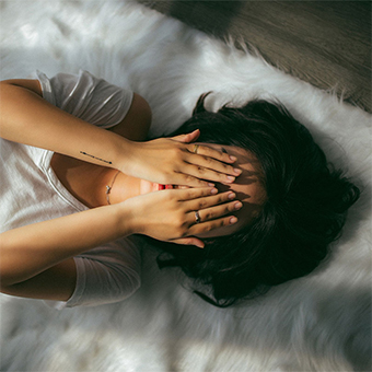 woman laying in bed with hands over eyes